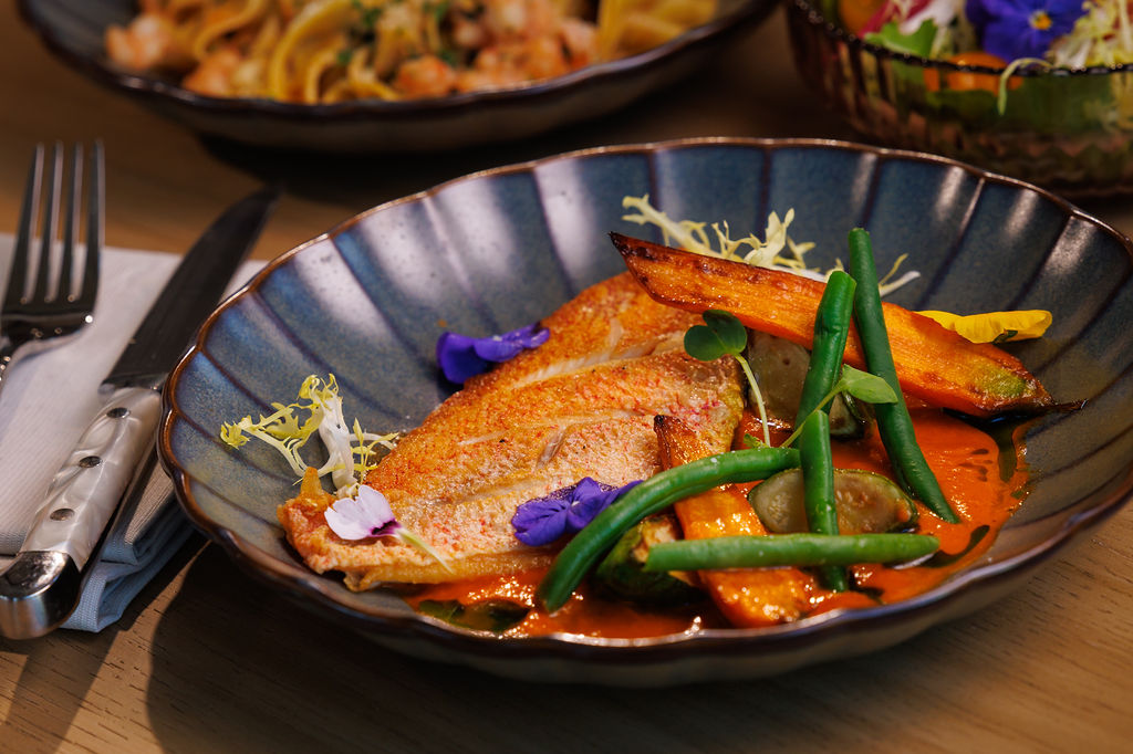Fish attractively plated on a black plate with garnish